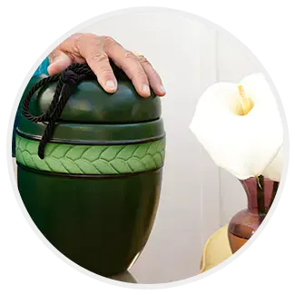 Hand resting on a green urn beside a white calla lily
